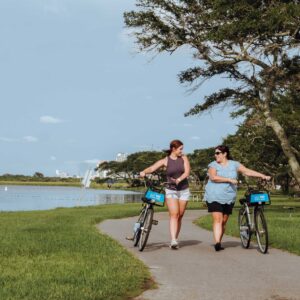 Two people riding bikes by a lake