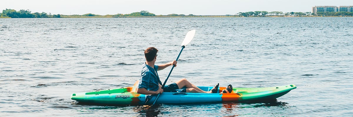 A person kayaking on calm waters at a Gulf Coast beach resort, enjoying outdoor recreation
