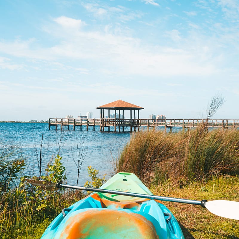 Kayak on a shore overlooking a peaceful bay and a wooden pier at a Gulf Coast beach resort